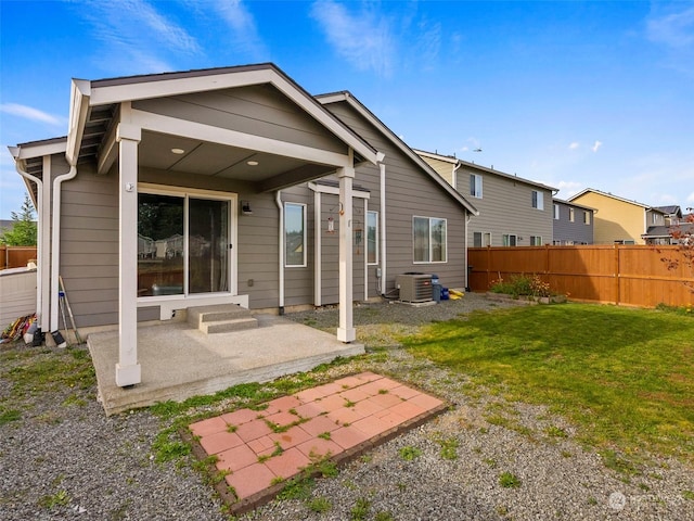 rear view of property with a lawn, a patio area, and central AC