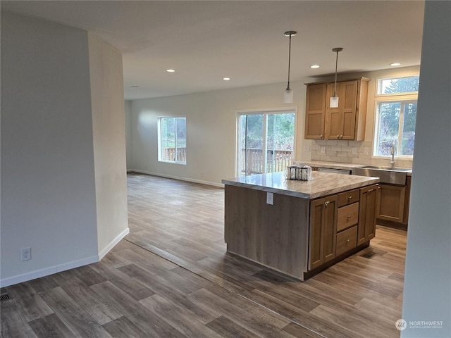 kitchen featuring dark hardwood / wood-style flooring, tasteful backsplash, sink, a center island, and hanging light fixtures