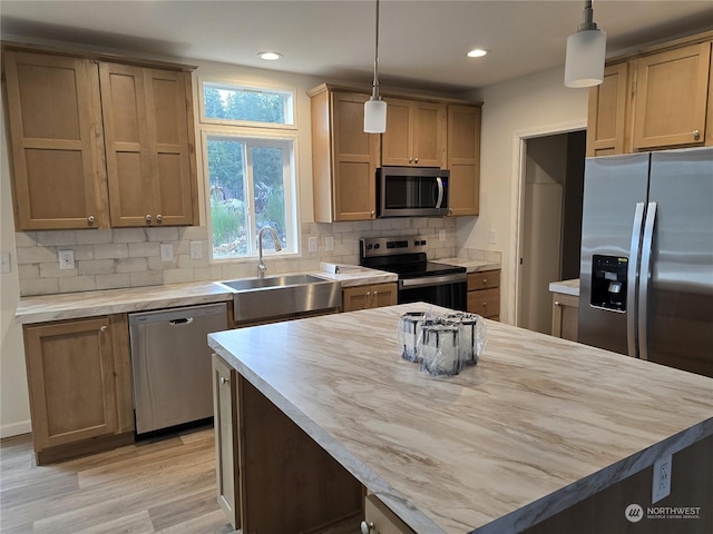 kitchen featuring light wood-type flooring, stainless steel appliances, sink, pendant lighting, and butcher block countertops