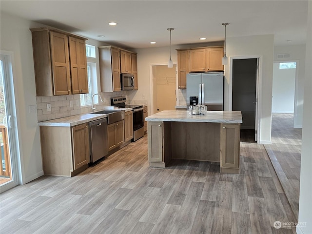 53 Newton Rd, Forks, WA 98331 - kitchen with stainless steel appliances, light wood finished floors, decorative backsplash, pendant lighting, and a kitchen island
