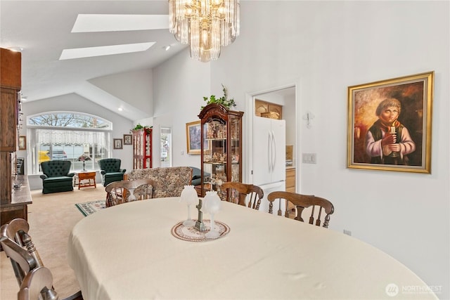 carpeted dining room featuring a skylight, an inviting chandelier, and high vaulted ceiling