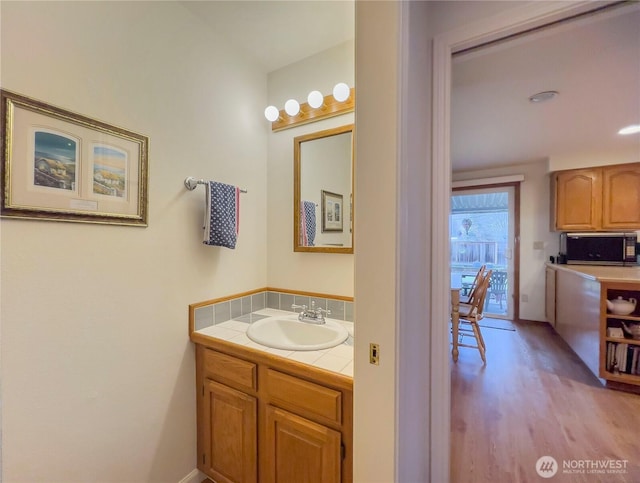 bathroom featuring vanity, decorative backsplash, and wood finished floors