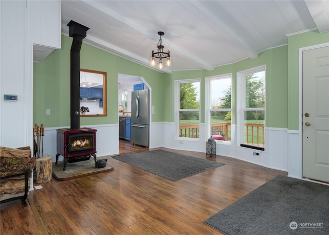 4495 Sequim Dungeness Way, Sequim, WA 98382 - unfurnished living room featuring a wood stove, wainscoting, wood finished floors, a chandelier, and beamed ceiling