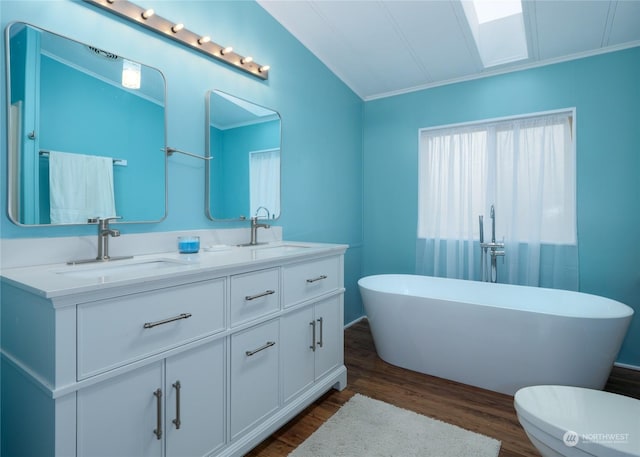 bathroom featuring hardwood / wood-style floors, vanity, a bathing tub, vaulted ceiling, and toilet