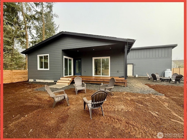 rear view of house with crawl space, fence, a fire pit, and a wooden deck