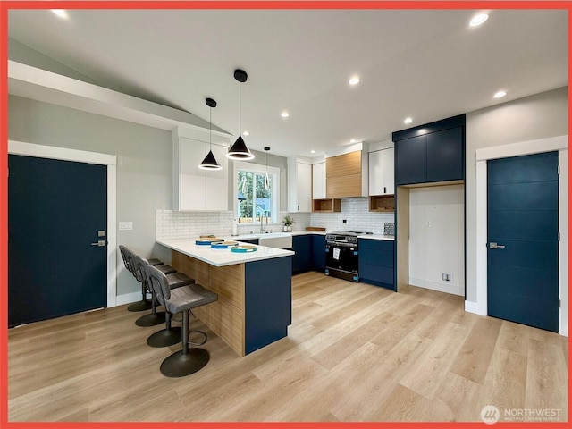 109 Sunrise Ave SE, Ocean Shores, WA 98569 - kitchen featuring stainless steel range, a peninsula, light countertops, decorative backsplash, and a kitchen breakfast bar