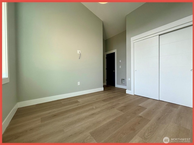 109 Sunrise Ave SE, Ocean Shores, WA 98569 - unfurnished bedroom featuring wood finished floors, lofted ceiling, baseboards, and a closet