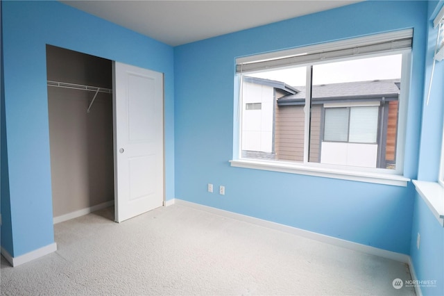 unfurnished bedroom featuring a closet and light colored carpet