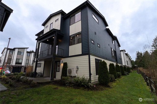 view of front of property featuring a front lawn, a balcony, and ac unit