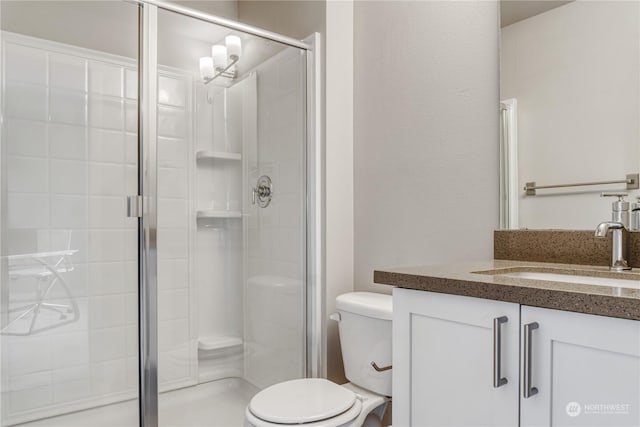 bathroom with toilet, vanity, and an enclosed shower