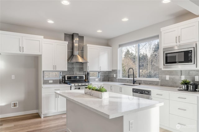 kitchen featuring appliances with stainless steel finishes, a center island, wall chimney range hood, tasteful backsplash, and sink