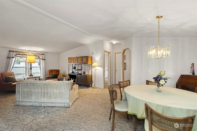 carpeted dining space with vaulted ceiling and an inviting chandelier