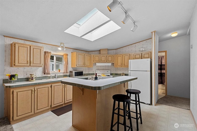 kitchen featuring a center island, tile countertops, white appliances, a breakfast bar area, and light brown cabinetry