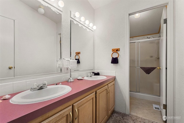 bathroom with decorative backsplash, a textured ceiling, vanity, and a shower with shower door