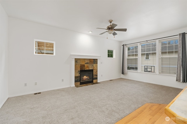 unfurnished living room featuring a tile fireplace, carpet flooring, and ceiling fan