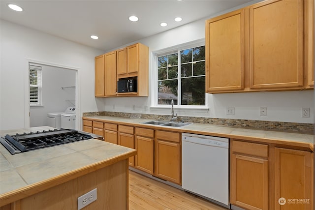 kitchen with white dishwasher, separate washer and dryer, sink, and tile countertops