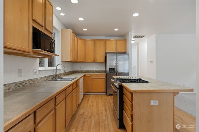 kitchen featuring appliances with stainless steel finishes, sink, tile countertops, light hardwood / wood-style flooring, and a kitchen island