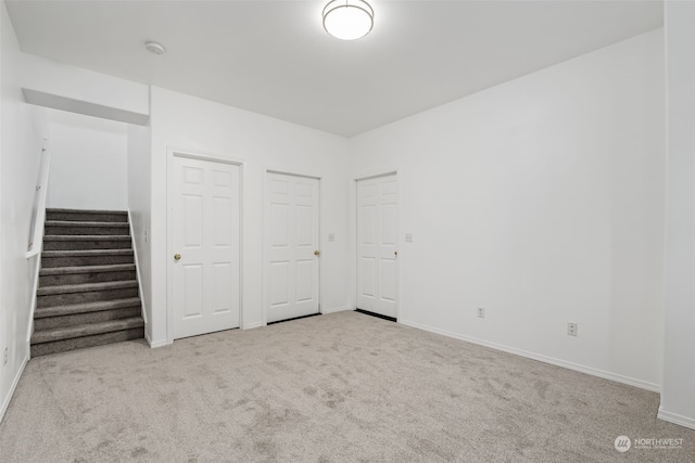 unfurnished bedroom featuring light carpet and two closets