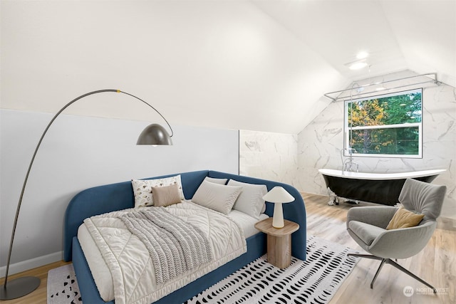 bedroom with light hardwood / wood-style floors and lofted ceiling