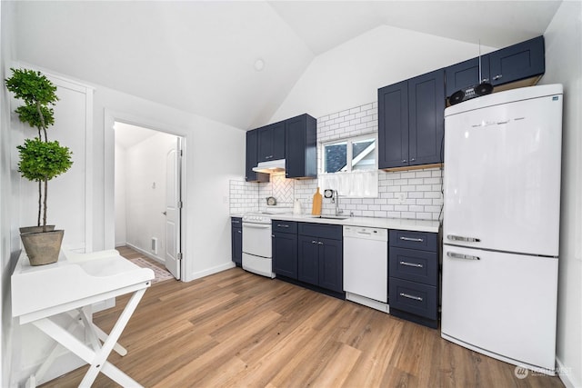 kitchen featuring blue cabinetry, lofted ceiling, sink, and white appliances