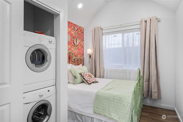 bedroom featuring dark wood-type flooring, stacked washer and dryer, and lofted ceiling