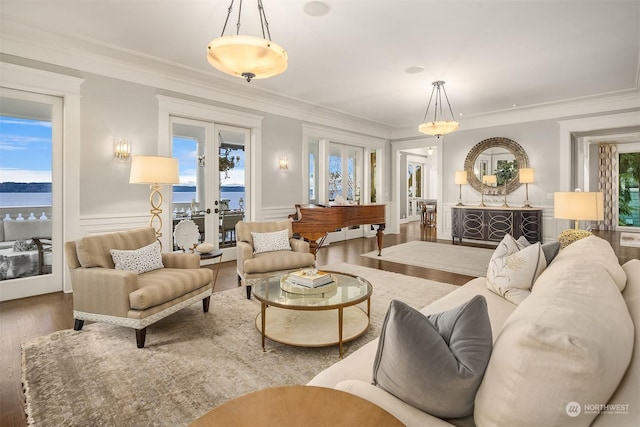 living room with french doors, a water view, crown molding, and plenty of natural light