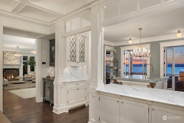 kitchen featuring dark wood-type flooring, pendant lighting, crown molding, white cabinets, and a water view