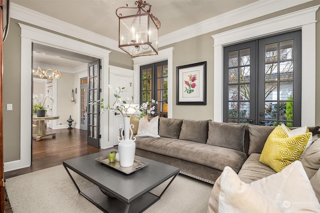 living room featuring a notable chandelier, dark wood-type flooring, french doors, and ornamental molding