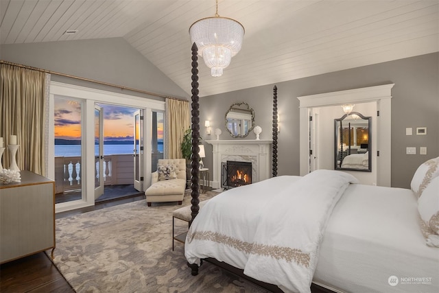 bedroom featuring an inviting chandelier, vaulted ceiling, a water view, access to exterior, and a premium fireplace