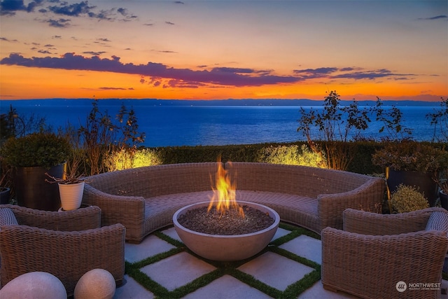 patio terrace at dusk featuring an outdoor fire pit and a water view