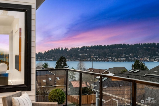 balcony at dusk featuring a water view