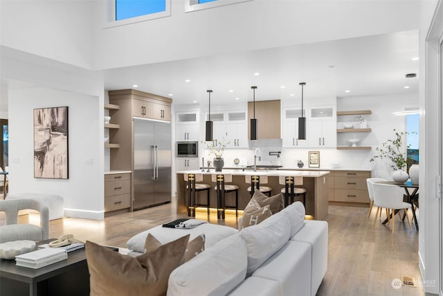 living room featuring a high ceiling, light wood-type flooring, and sink