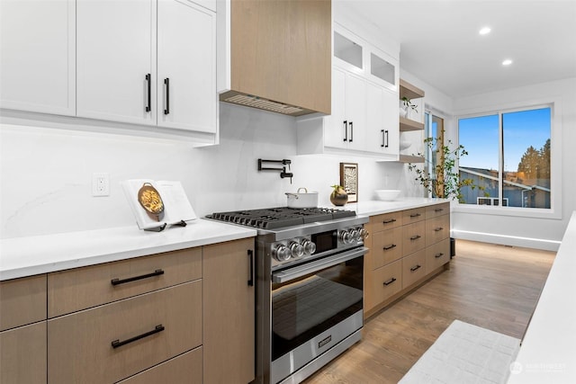 kitchen with high end range, light wood-type flooring, and white cabinetry