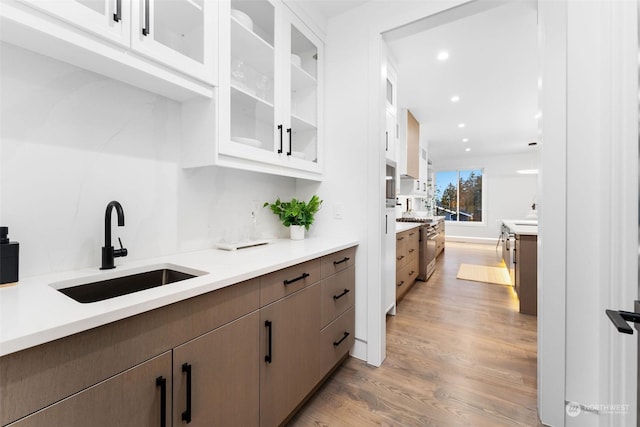 kitchen featuring high end range, white cabinets, light hardwood / wood-style flooring, and sink