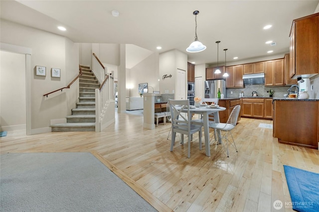 kitchen featuring dark countertops, light wood-type flooring, appliances with stainless steel finishes, and brown cabinets