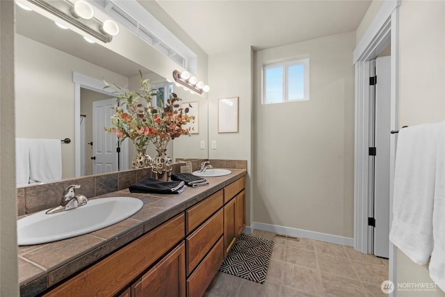 bathroom featuring double vanity, visible vents, baseboards, and a sink