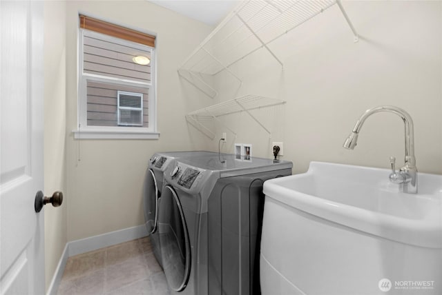 washroom featuring light tile patterned floors, laundry area, a sink, baseboards, and washer and clothes dryer