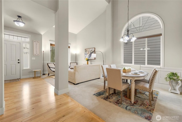 dining space with a chandelier, high vaulted ceiling, and wood finished floors