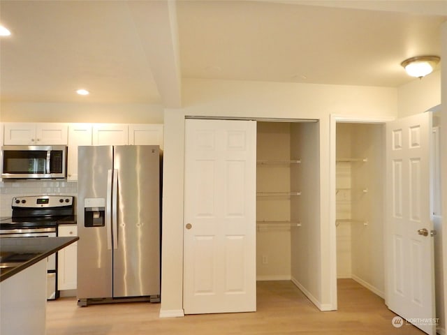 kitchen with white cabinets, light wood-type flooring, stainless steel appliances, and tasteful backsplash