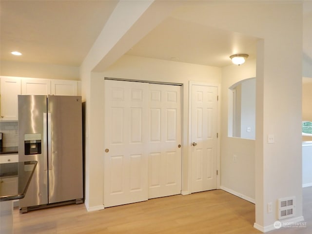 kitchen featuring white cabinetry, backsplash, stainless steel fridge, and light hardwood / wood-style floors