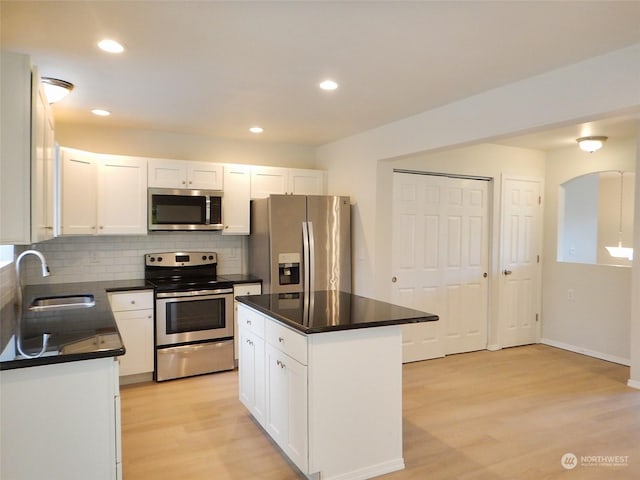 kitchen featuring white cabinetry, sink, light hardwood / wood-style flooring, a kitchen island, and appliances with stainless steel finishes