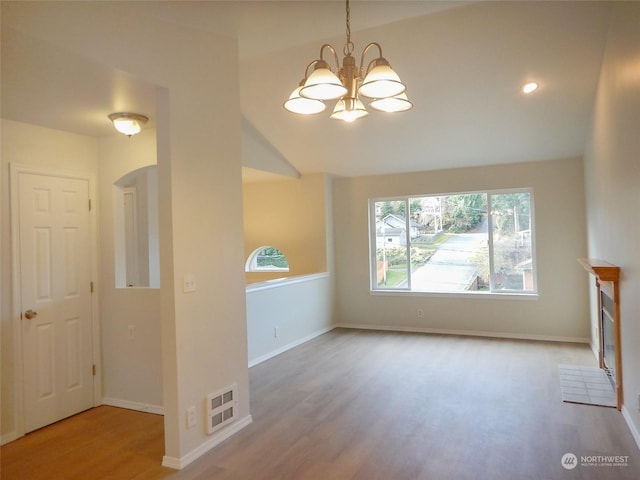 unfurnished living room with light hardwood / wood-style flooring and a notable chandelier