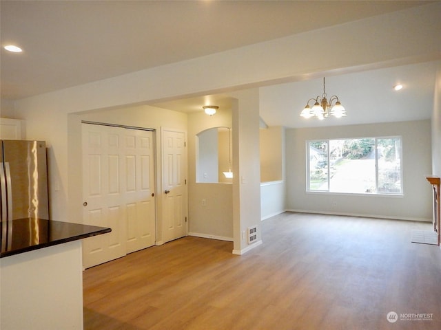 kitchen with stainless steel refrigerator, a chandelier, decorative light fixtures, and light wood-type flooring