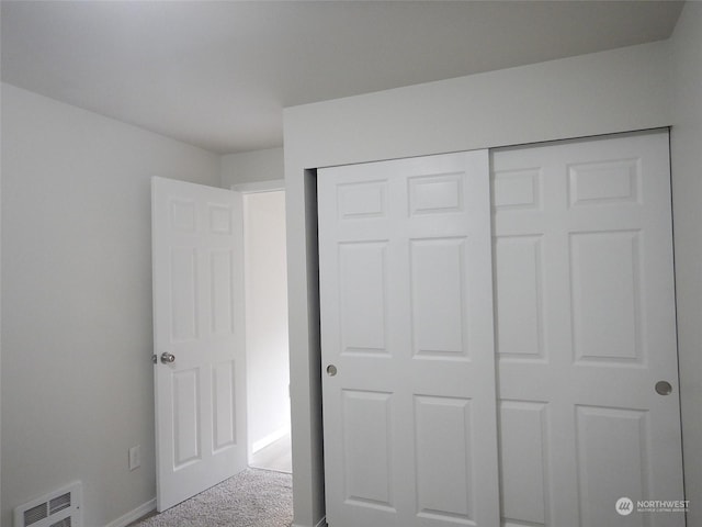 unfurnished bedroom featuring light colored carpet and a closet