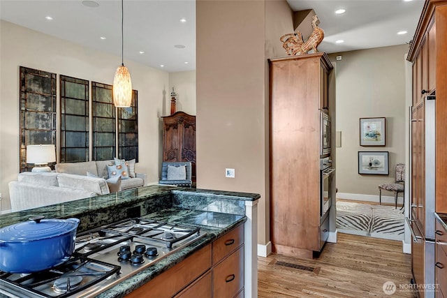 2031 42nd Ave E, Seattle, WA 98112 - kitchen with light wood-type flooring, appliances with stainless steel finishes, recessed lighting, brown cabinets, and hanging light fixtures