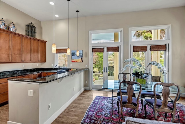 2031 42nd Ave E, Seattle, WA 98112 - kitchen with french doors, brown cabinets, a peninsula, dark countertops, and pendant lighting