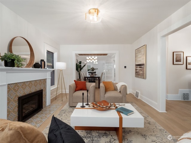 living room featuring a fireplace, an inviting chandelier, and light hardwood / wood-style flooring