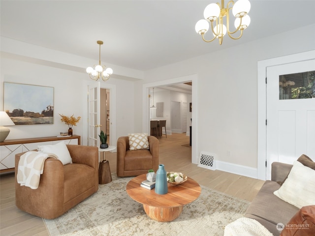 living room with light hardwood / wood-style floors and a notable chandelier