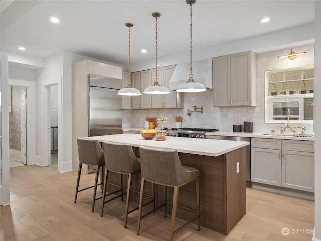 kitchen with sink, a kitchen island, backsplash, and light hardwood / wood-style floors