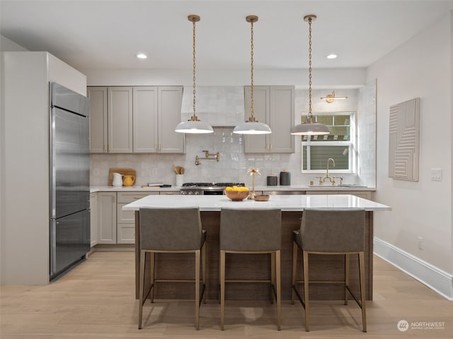 kitchen with light hardwood / wood-style floors, built in fridge, backsplash, and sink